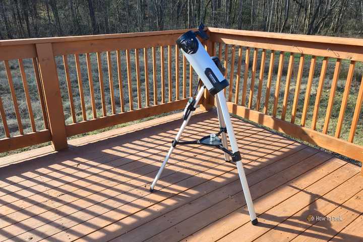 A Celestron 114LCM telescope sitting on a deck.