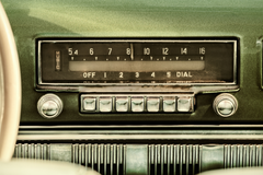 Retro styled image of an old car radio inside a green classic car.