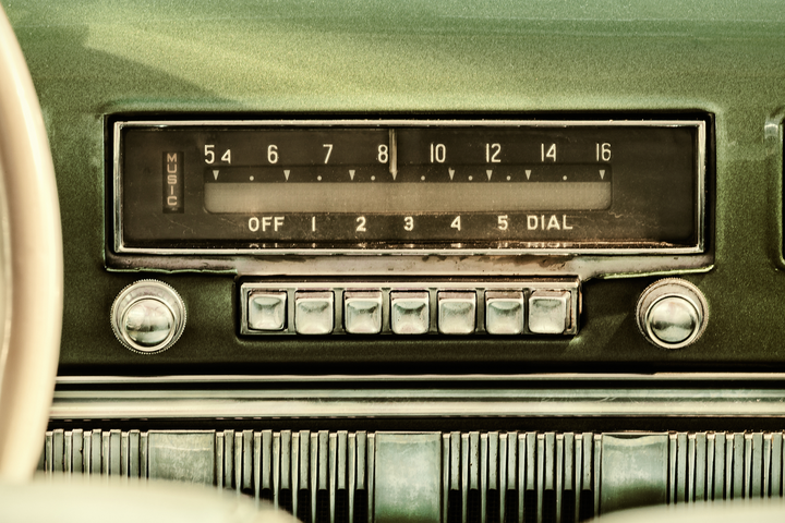 Retro styled image of an old car radio inside a green classic car.