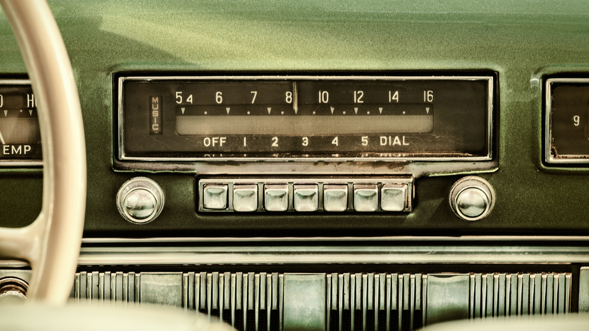 Retro styled image of an old car radio inside a green classic car.