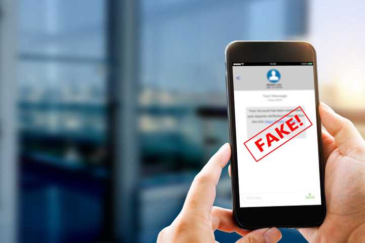 Man holding phone showing a fake scam text message