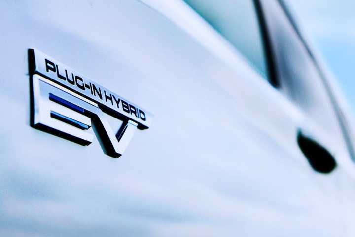Close-up shot of the badging on the side of a white 2025 Mitsubishi Outlander Plug-in Hybrid.