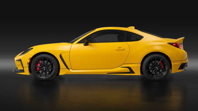 Side profile shot of a yellow 2026 Toyota GR86 Yuzu in a studio with a black backdrop.