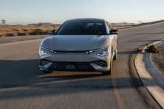 Front view of a gray 2025 Kia EV6 driving taking a corner in a road.