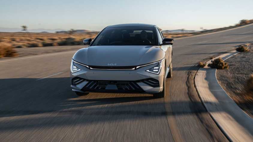 Front view of a gray 2025 Kia EV6 driving taking a corner in a road.