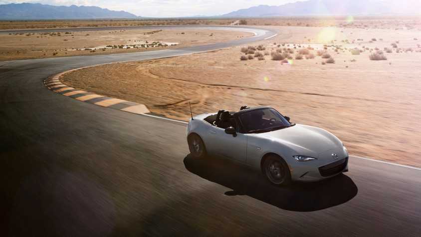 Dynamic front 3/4 shot of a silver 2024 Mazda MX-5 on a racetrack in the desert.