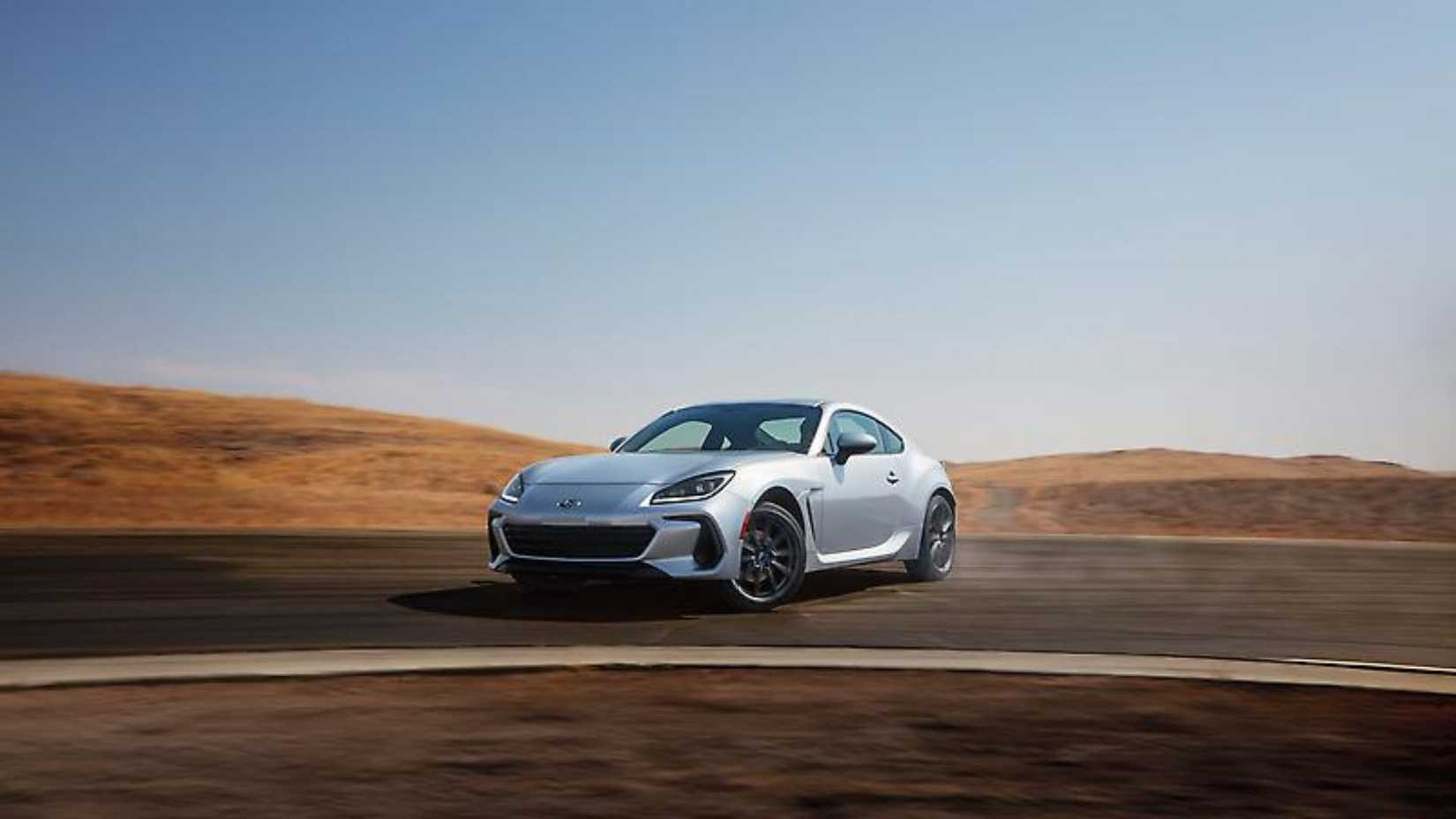 Dynamic front 3/4 shot of a silver 2024 Subaru BRZ drifting around a corner on a racetrack.