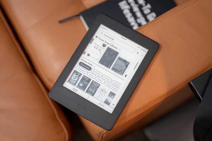 2015 Amazon Kindle Paperwhite eReader sitting on a couch showing the home screen.