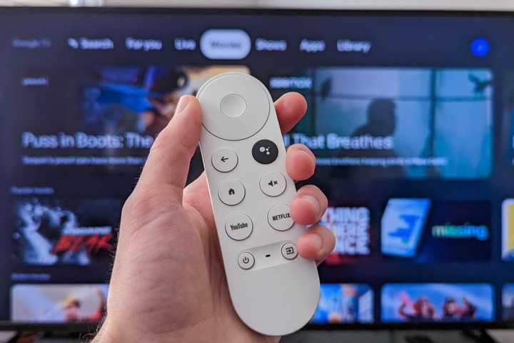 Person holding a Chromecast remote infront of a tv with Google TV open.