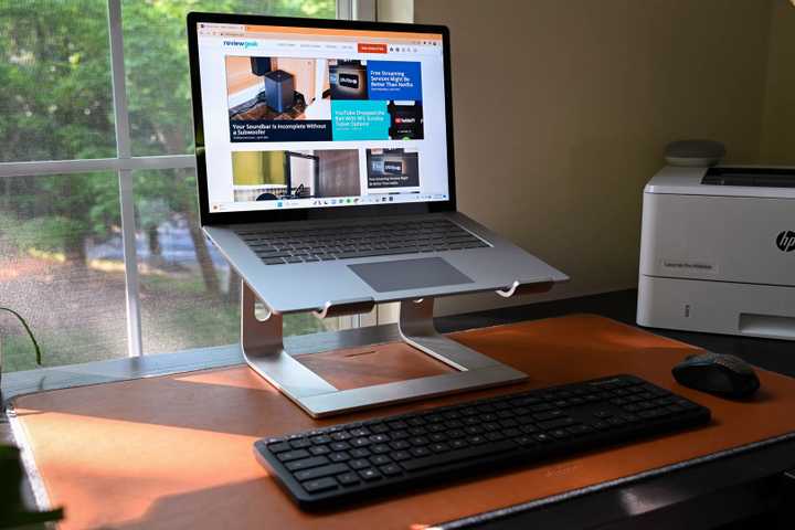 A work from home setup with a Microsoft Surface Laptop set up on a laptop stand with a mouse and keyboard.