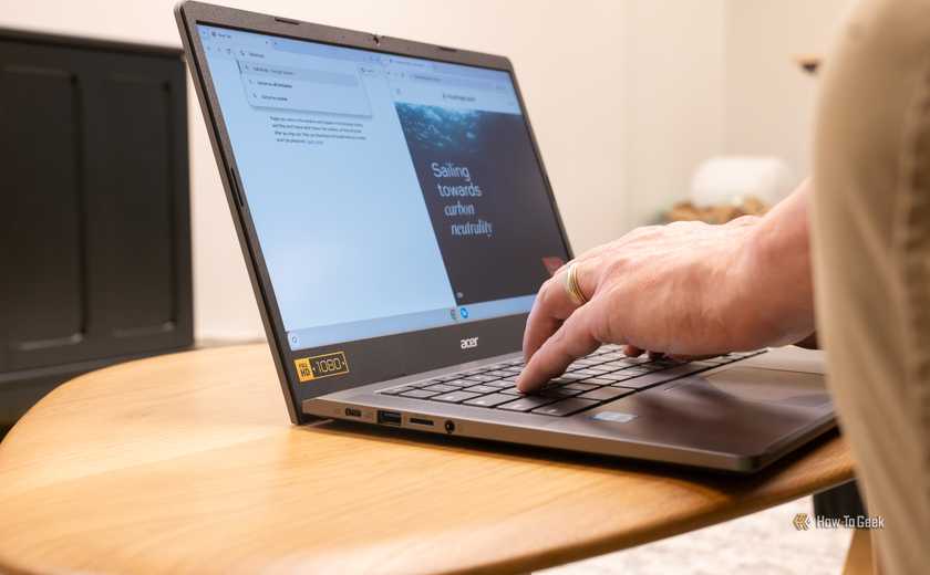 An Acer Chromebook sitting on a table with someone typing on it.