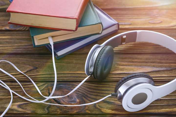 A pair of headphones connected to physical books.