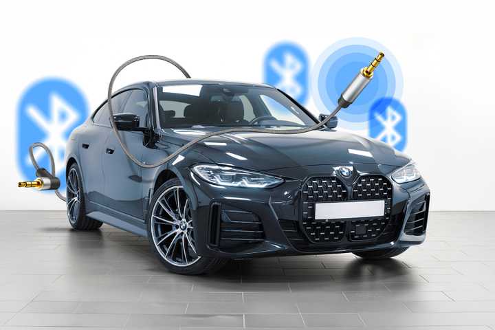 A car surrounded by an auxiliary cable with blurred Bluetooth icons in the background.