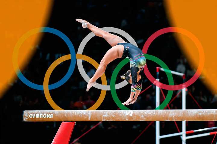 A gymnast performing with the Olympics logo in the background.