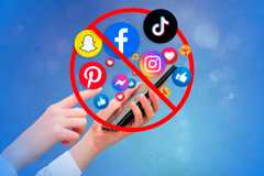 A hand holding a smartphone and a lot of emojis and social media symbols coming out of the smartphone with a prohibited symbol in front of them