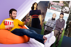 A man lounging on a beanbag, holding a TV remote and a bucket of popcorn, with TV show covers next to him.