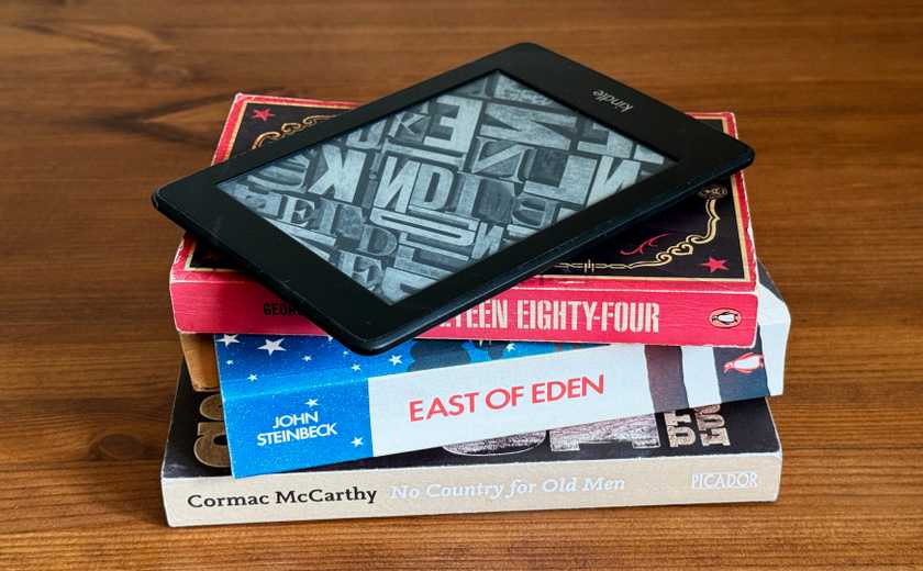A stack of books with a Kindle eReader on top of them.