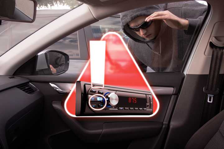 A thief looking through a car window and an alert icon with a stereo inside.