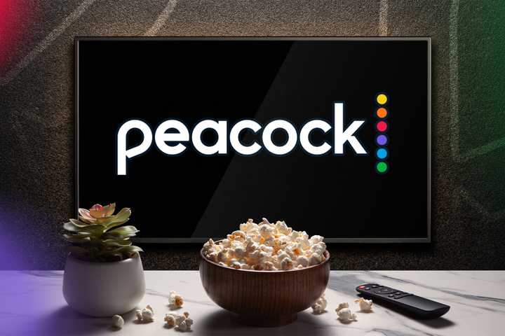 A TV displaying the Peacock logo, with a bowl of popcorn, a remote control, and a plant in front.