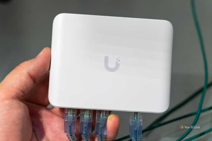 The Unifi Flex Mini 2.5G Ethernet switch with Ethernet cables plugged in being held in a hand.