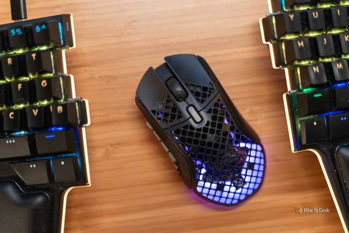 The SteelSeries Aerox 9 wireless MMO gaming mouse between two keyboard halves top down.