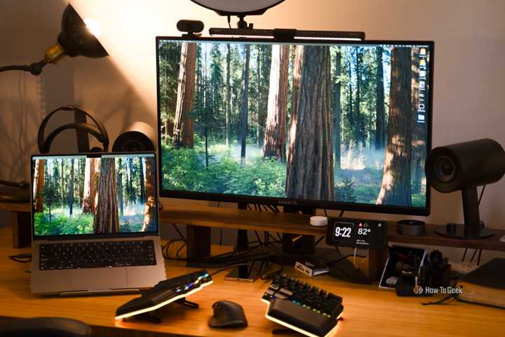 A desk setup featuring a MacBook Pro and a 32-inch 4K monitor with a split keyboard and mouse on the desk.