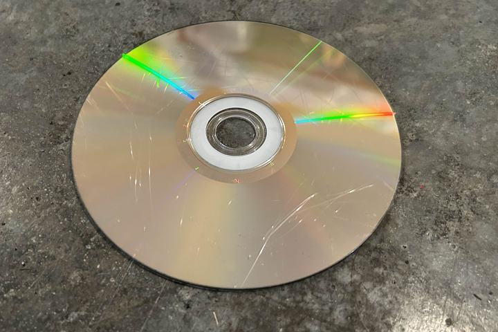 A_scratched_disc_on_a_dusty_grey_garage_floor
