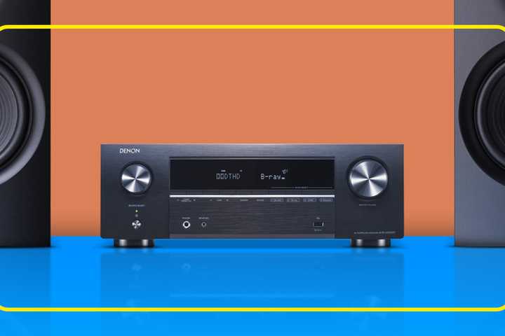 An AV receiver on a surface with two speakers beside it.