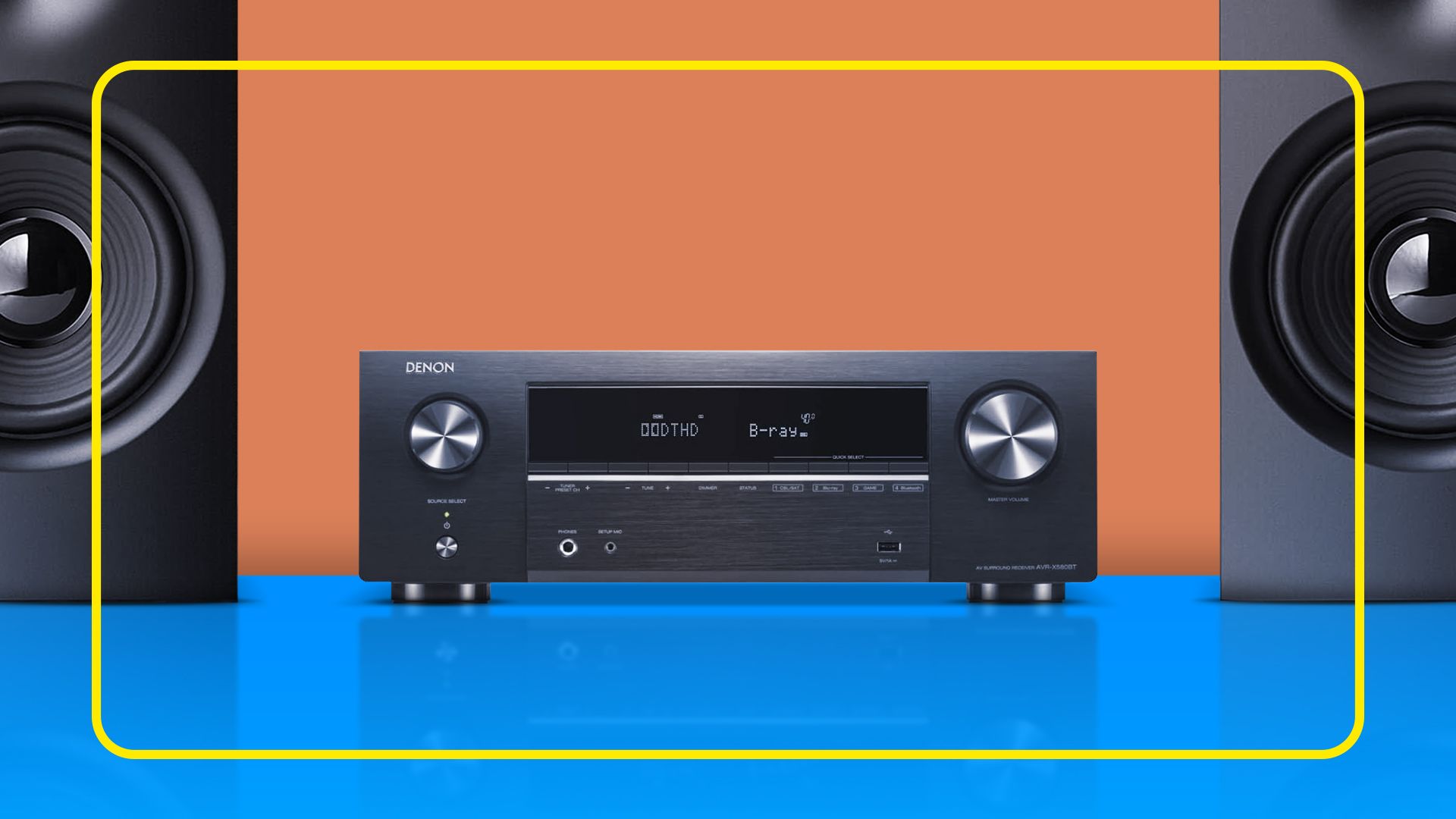 An AV receiver on a surface with two speakers beside it.