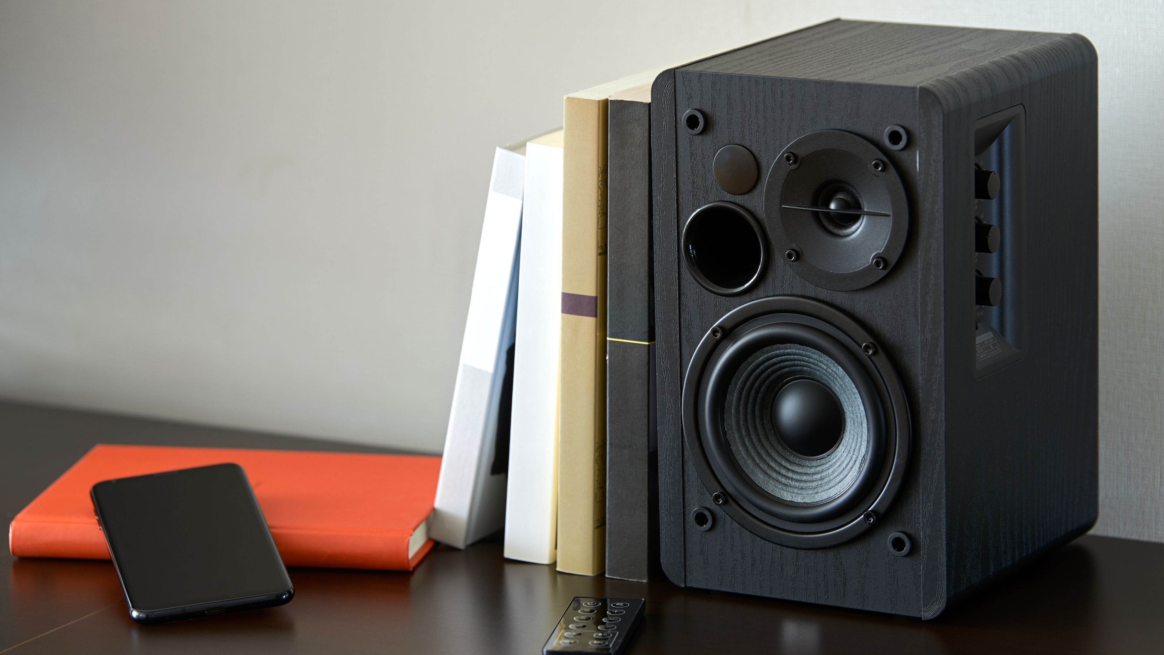 Bookshelf speaker with books and iPhone.