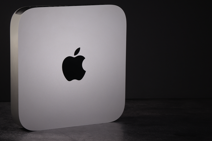 A Mac Mini standing on its side on a dark background.