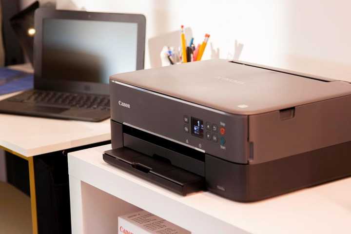 Canon Prixma next to a laptop on a desk.