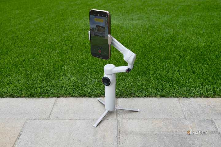 Insta360 Flow 2 gimbal standing on its tripod outside.