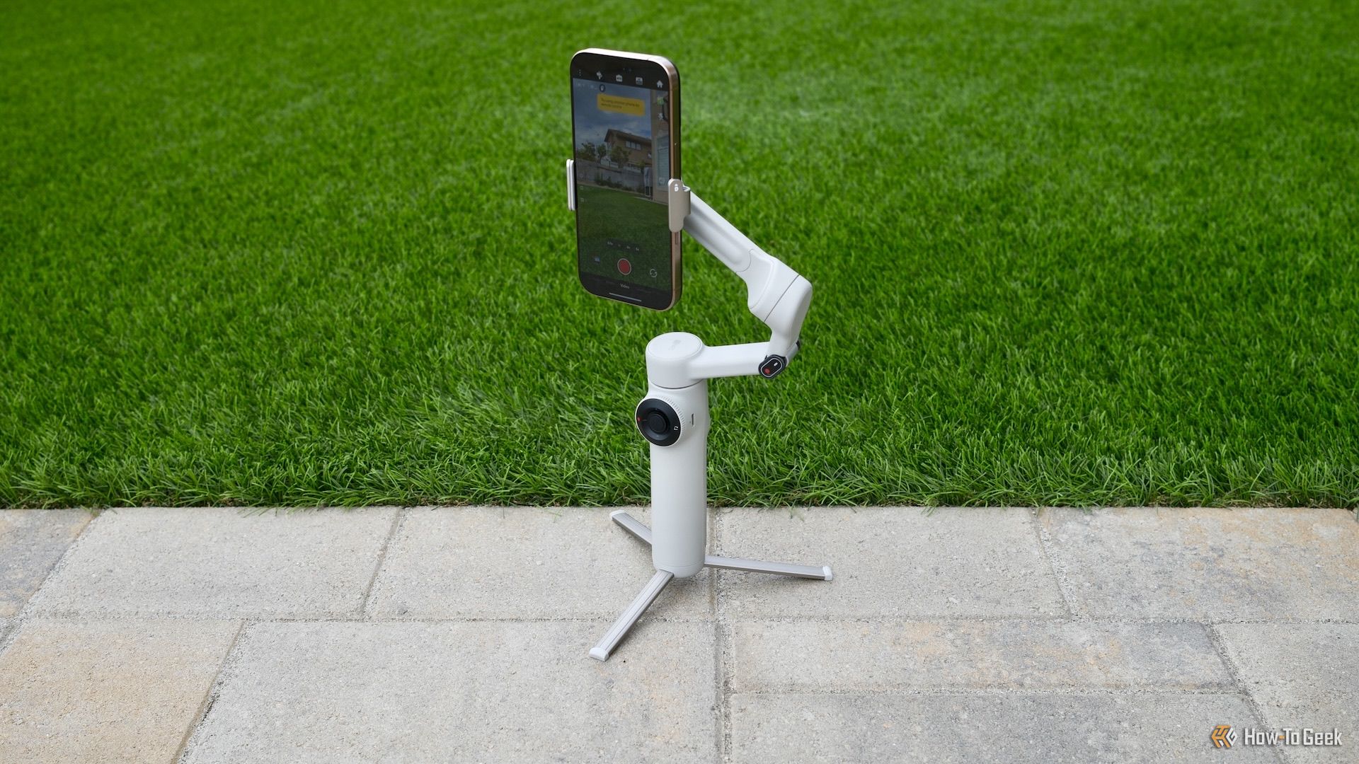 Insta360 Flow 2 gimbal standing on its tripod outside.