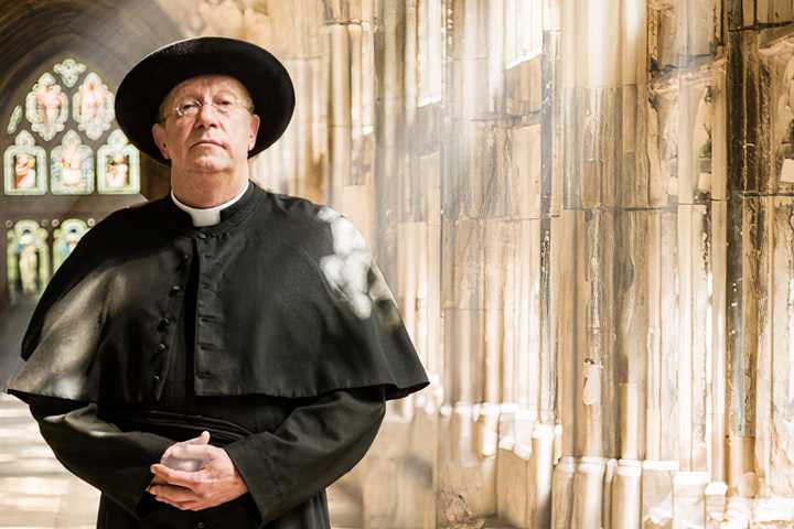 Father Brown appearing inside a church with sunlight coming through the windows