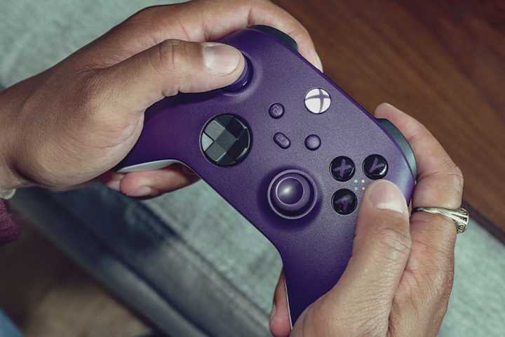 Hands holding a purple Xbox Wireless Controller.
