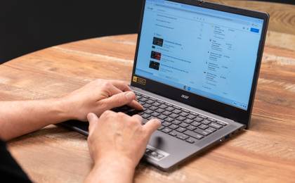 Hands typing on an Acer Chromebook on a table.