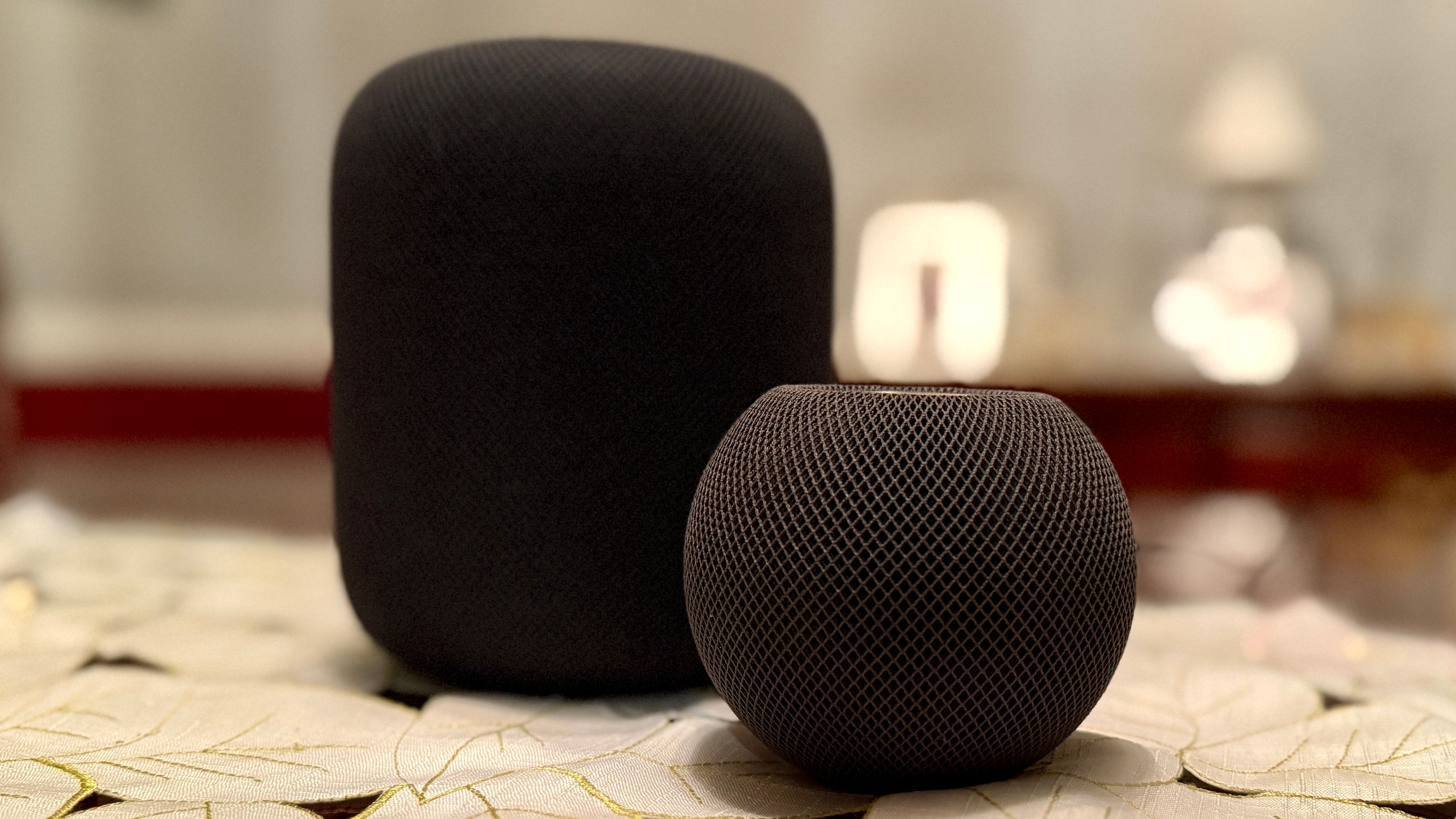 Black HomePod and HomePod mini on a table next to one another.
