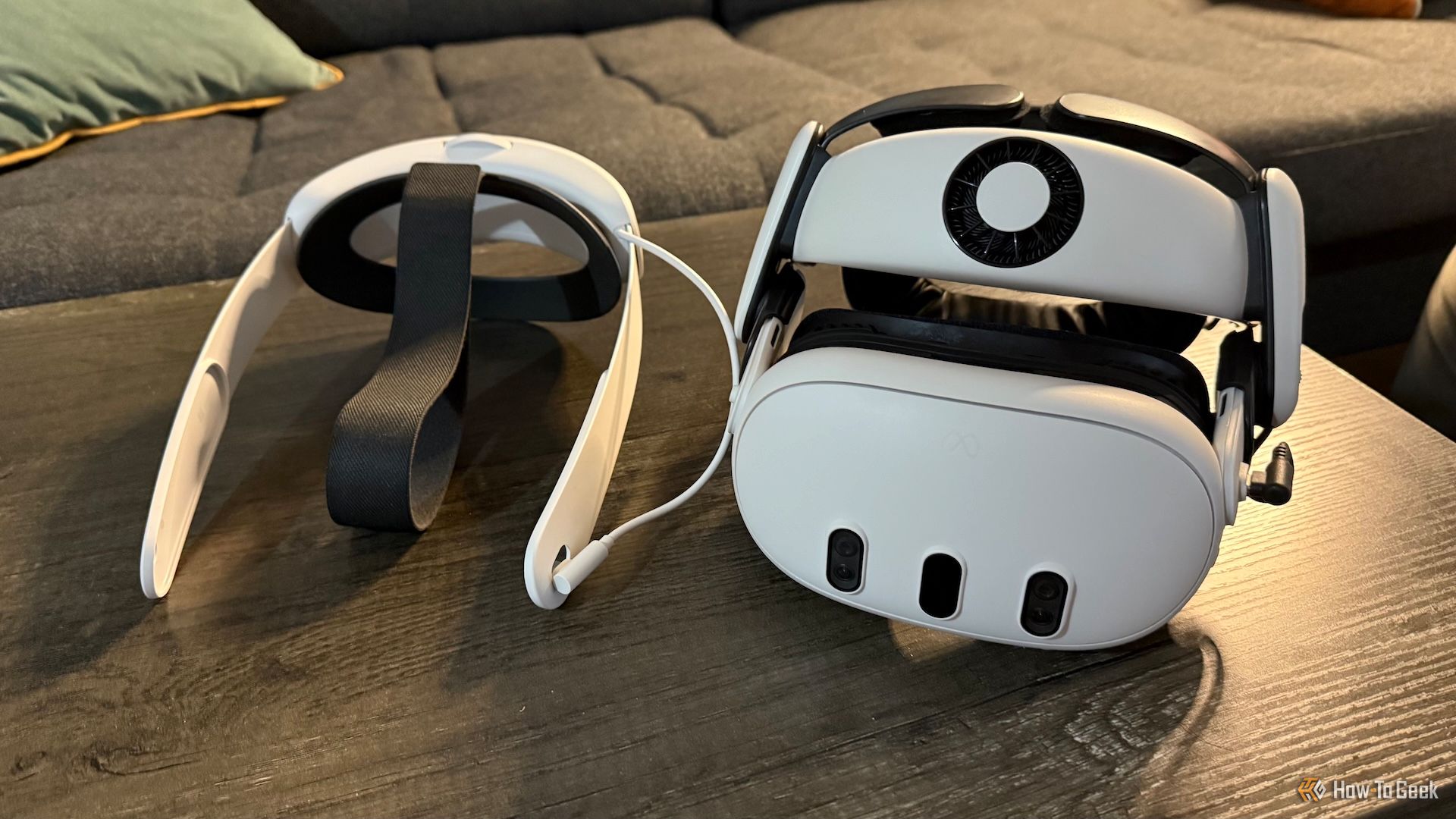 A Meta Quest 3 with a BOBOVR S3 Pro halo strap and a Meta Quest 3 Elite Strap with Battery on a table from the front.