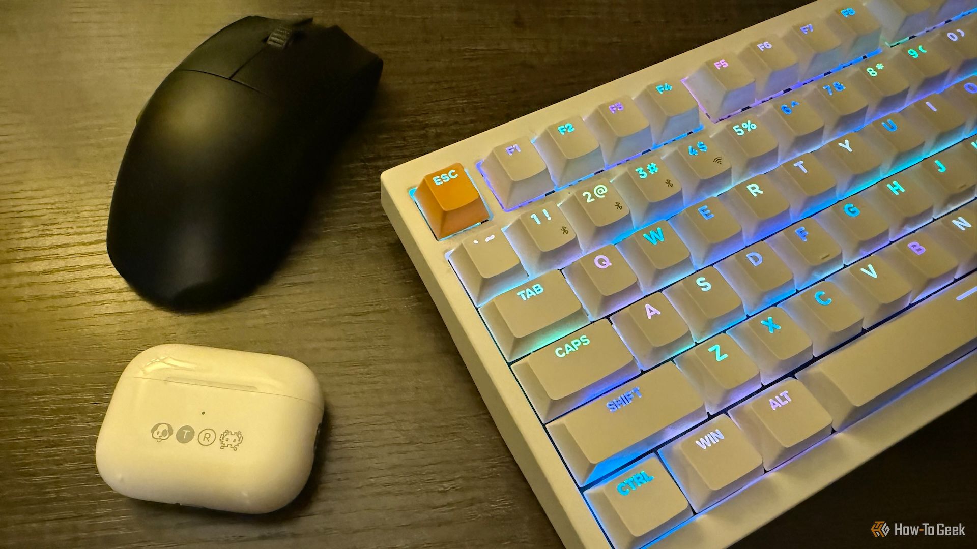 Apple AirPods Pro in an engraved case, a Razer Viper V3 Pro wireless mouse, and a Keychron K2 HE wireless magnetic keyboard on a table.