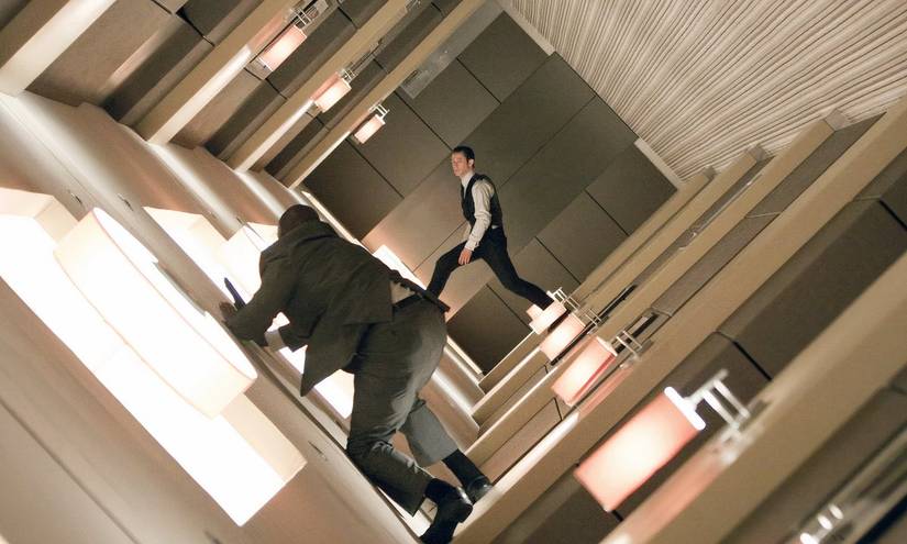 Two characters running around a spiraling hallway in the movie Inception.
