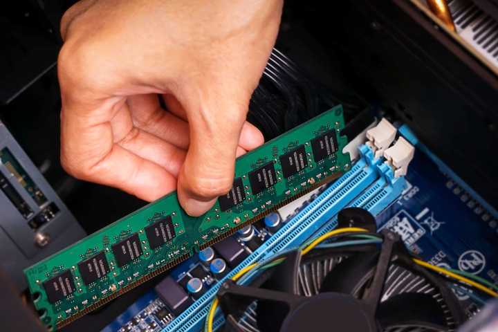 Someone installing a stick of RAM in a computer.