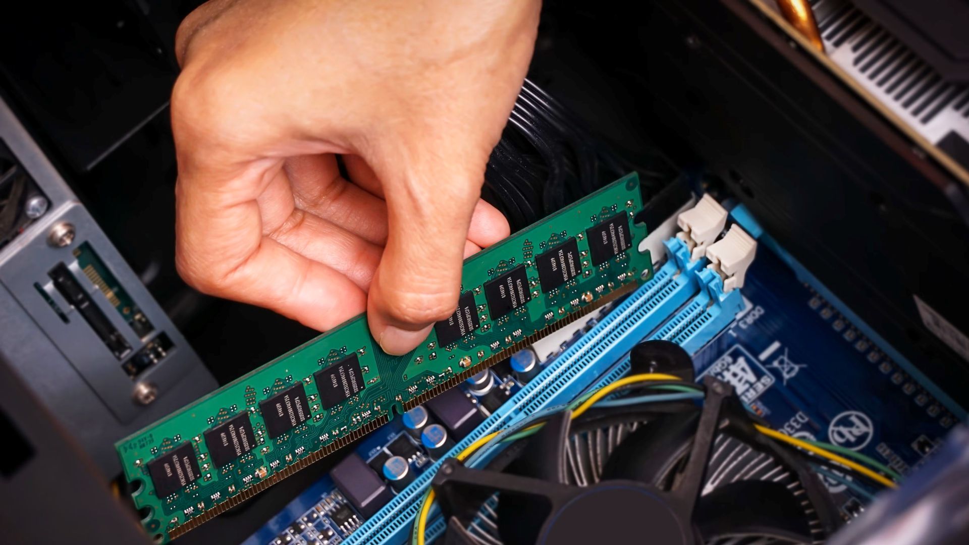 Someone installing a stick of RAM in a computer.