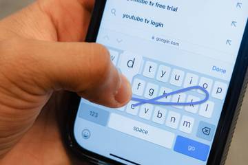 A person typing on an iPhone keyboard.