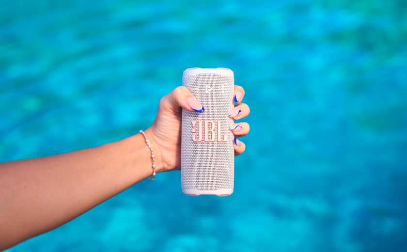 Person holding the JBL Grip speaker above a pool. 
