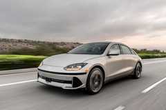 Dynamic front 3/4 shot of a silver 2025 Hyundai Ioniq 6 driving on a country road.