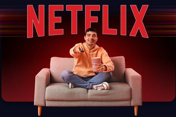 Man sitting on a couch holding popcorn and a remote control, smiling while watching TV, with a large red Netflix logo in the background.