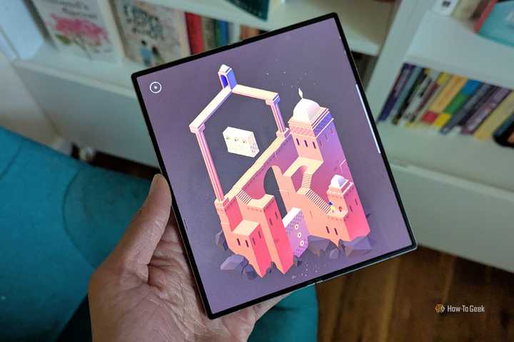 Monument Valley 2 on a Galaxy Z Fold 6 with books in the background.