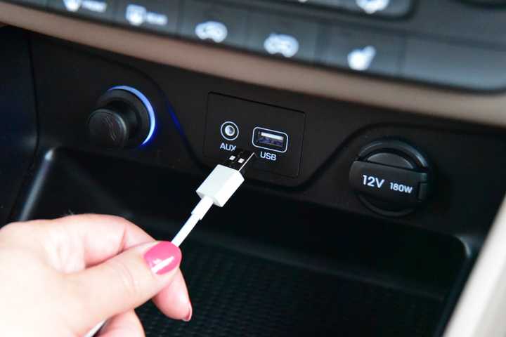 Hand plugging a USB cable into a car dashboard port