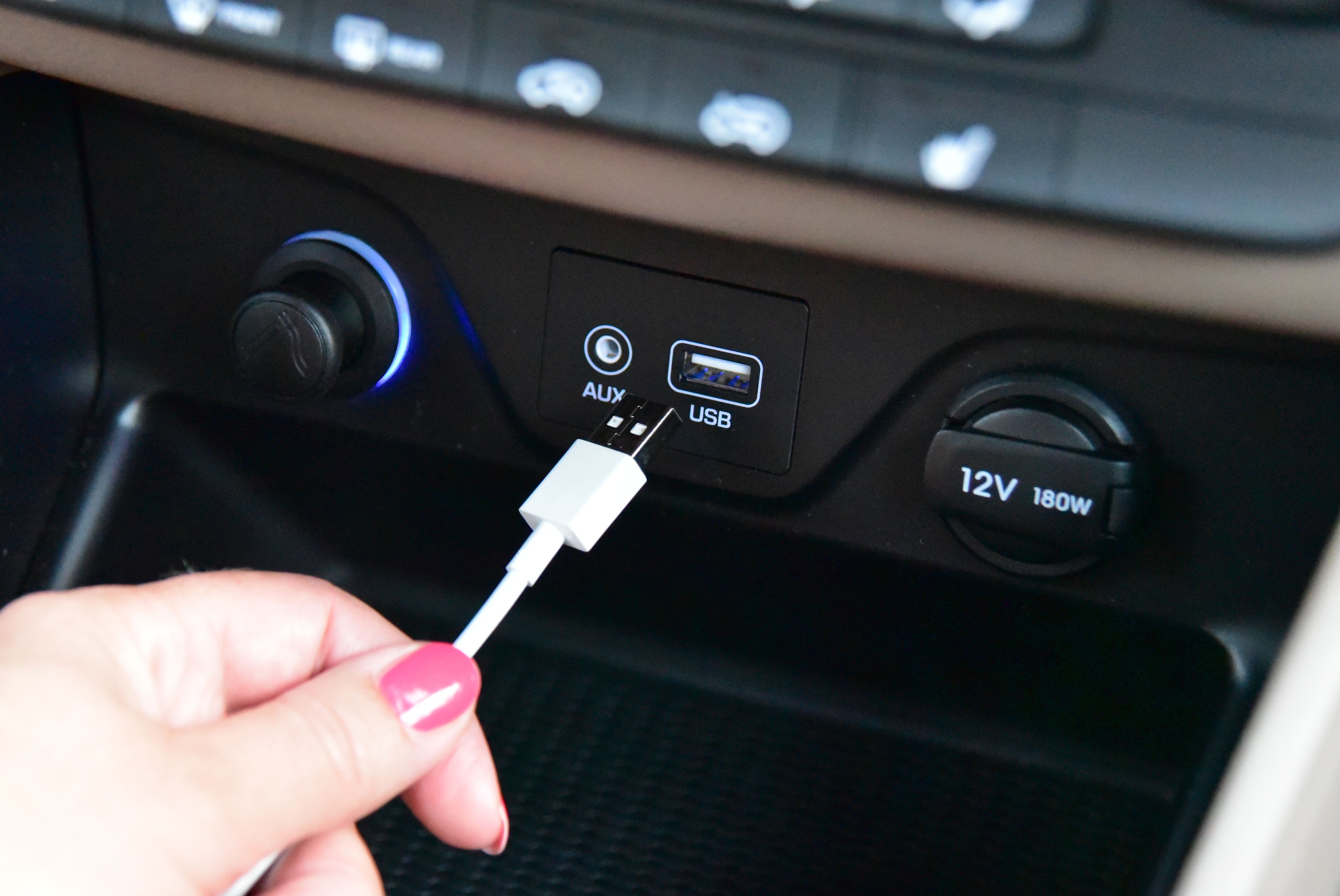 Hand plugging a USB cable into a car dashboard port